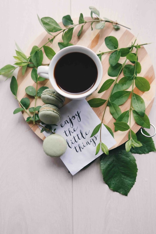 the image shows a close up of a cup of coffee and sweet treats on a table featuring a note saying enjoy the small things and the blog post is about powerful ways to relax after work
