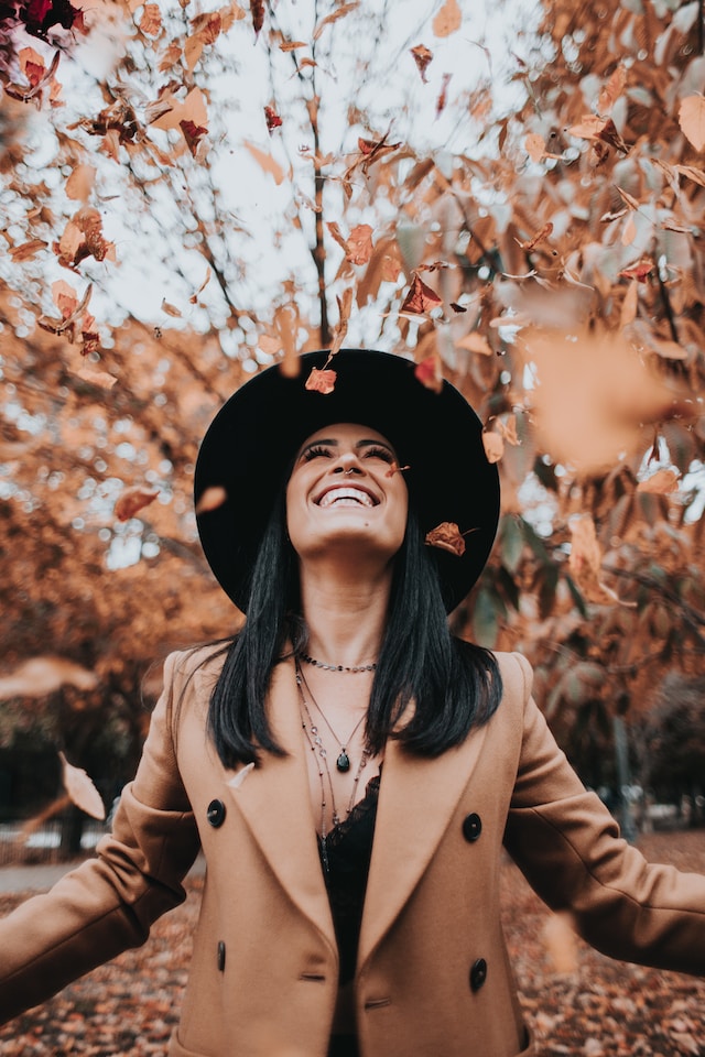 picture showing woman with dark hair and brown coat in autumn nature setting blog post is about autumn essentials self-care products for busy women