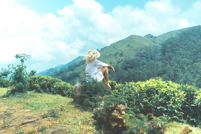 image showing a woman sitting on a rock in the middle of a stunning nature setting mindfulness and grounding connect with nature