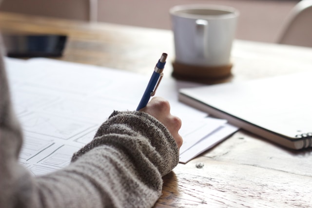 image shows a close up of a female hand writing onto a piece of paper blog post is about positive morning affirmations