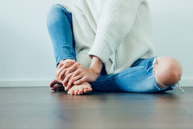 image showing a close up of a woman dressed in jeans and a white pullover sitting on a wooden floor blog post is about positive morning affirmations to start the day