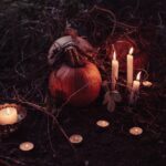 picture shows a display of a few candles and pumpkins in a Halloween setting blog post is about spooky home decor for Halloween and all year