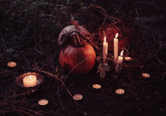 picture shows a display of a few candles and pumpkins in a Halloween setting blog post is about spooky home decor for Halloween and all year