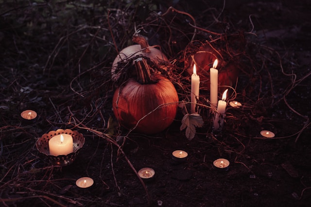 picture shows a display of a few candles and pumpkins in a Halloween setting blog post is about spooky home decor for Halloween and all year