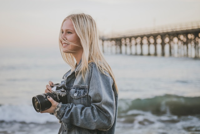 blonde woman walking along a beach taking pictures blog post is about benefits of solo travel