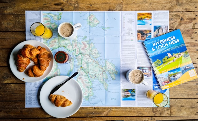 image showing a map, a cup of coffee, a croissant and a travel guide spread out on a table blog post is about solo trip benefits