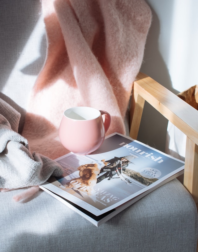 image shows a close up of a chair, a women's magazine and a cup of tea the blog post is about personal growth ideas and this image represents self care