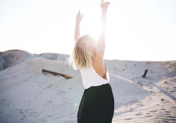 image showing a blonde woman standing in the sand dunes her arms are reaching up to the sky, the blog post is about personal growth ideas