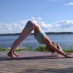 image showing woman doing morning yoga next to a lake the blog post is about morning yoga stretches from certified yoga teacher nicolle spohn