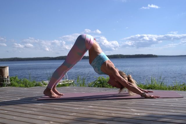 image showing woman doing morning yoga next to a lake the blog post is about morning yoga stretches from certified yoga teacher nicolle spohn