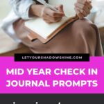 pinterest pin image that shows a close up of a woman journaling introducing this blog post about a mid year check in with self growth journal prompts that inspire change and transformation